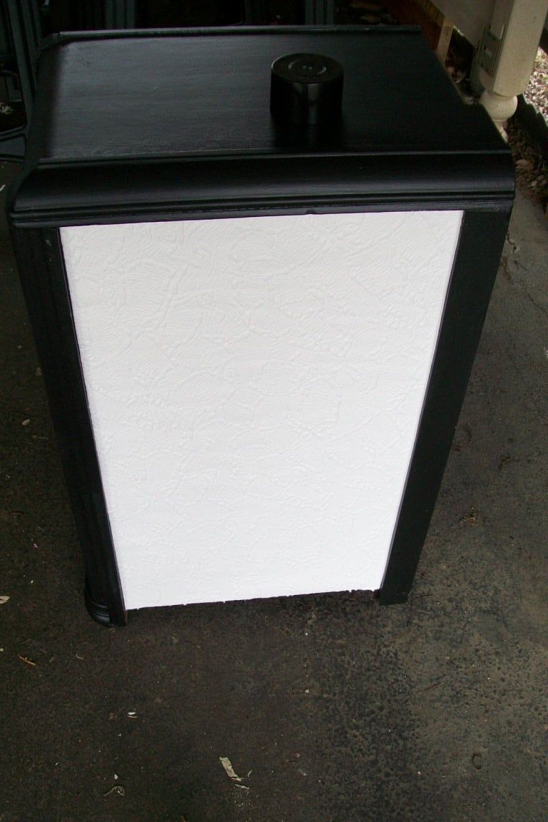 side of vanity with white textured wallpaper