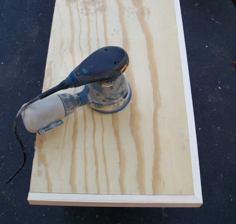 an orbital sander on the plywood desktop