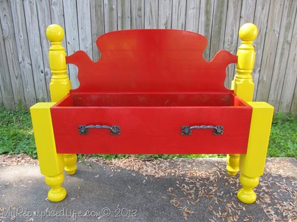 repurposed headboard into a red flower bed
