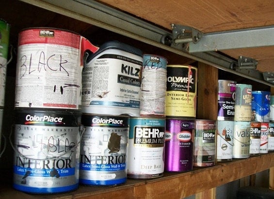 a dozen paint cans stored in a garage