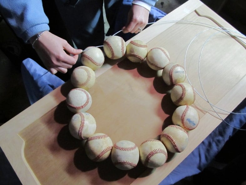 fourteen baseballs in a circle on a wire