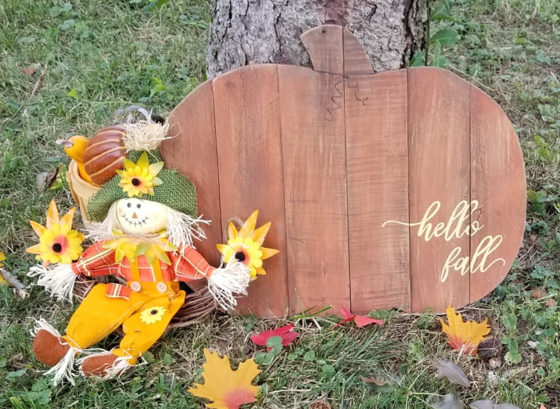 hello fall pumpkin sign leaning against a tree