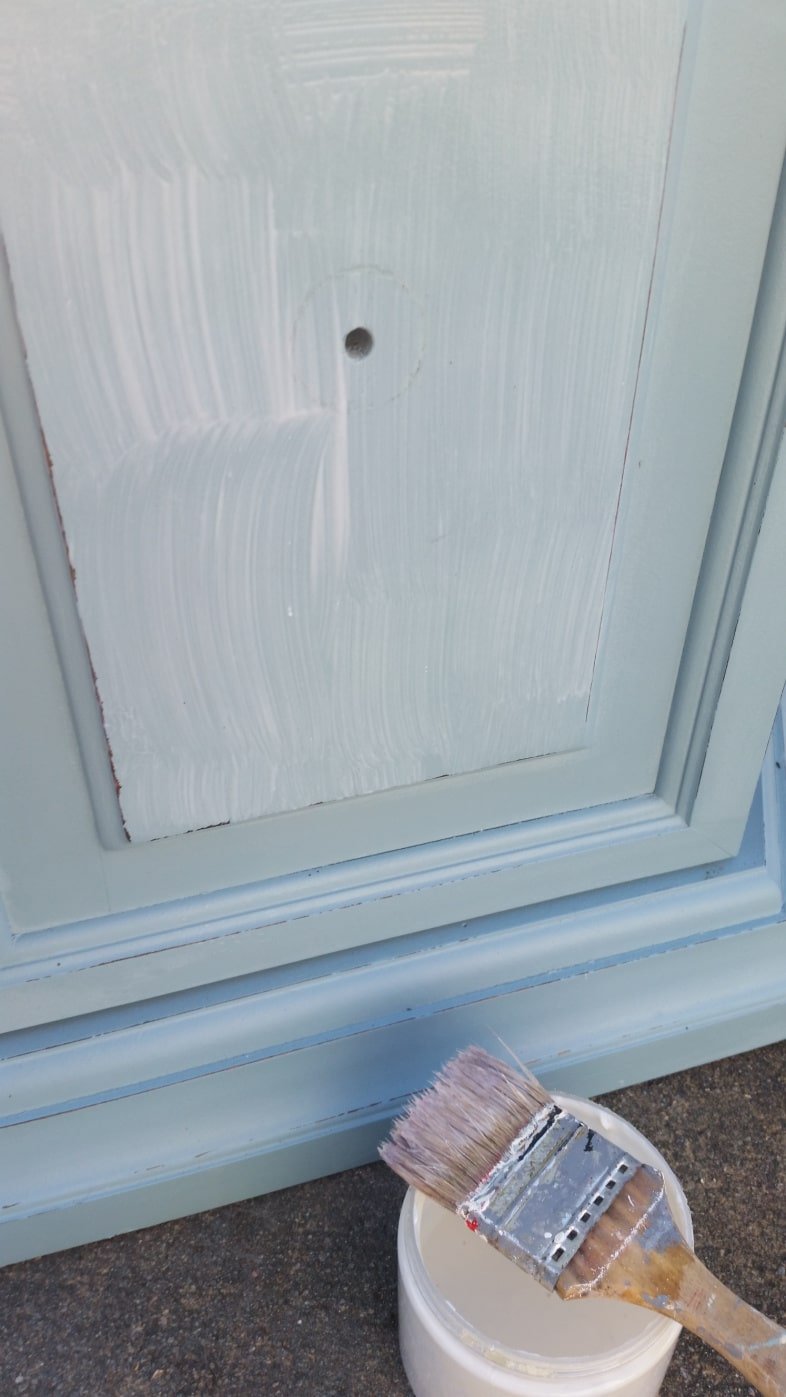 applying decoupage medium to the front of the table door with a chip brush