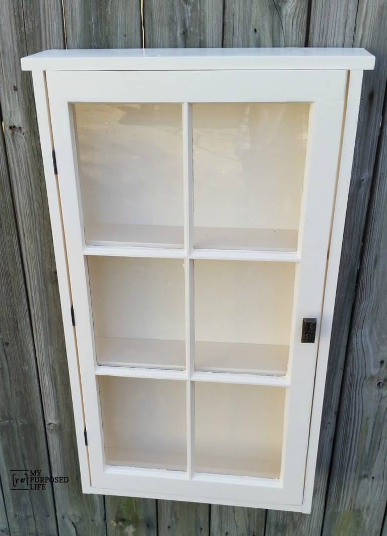 white window cabinet hanging on a fence