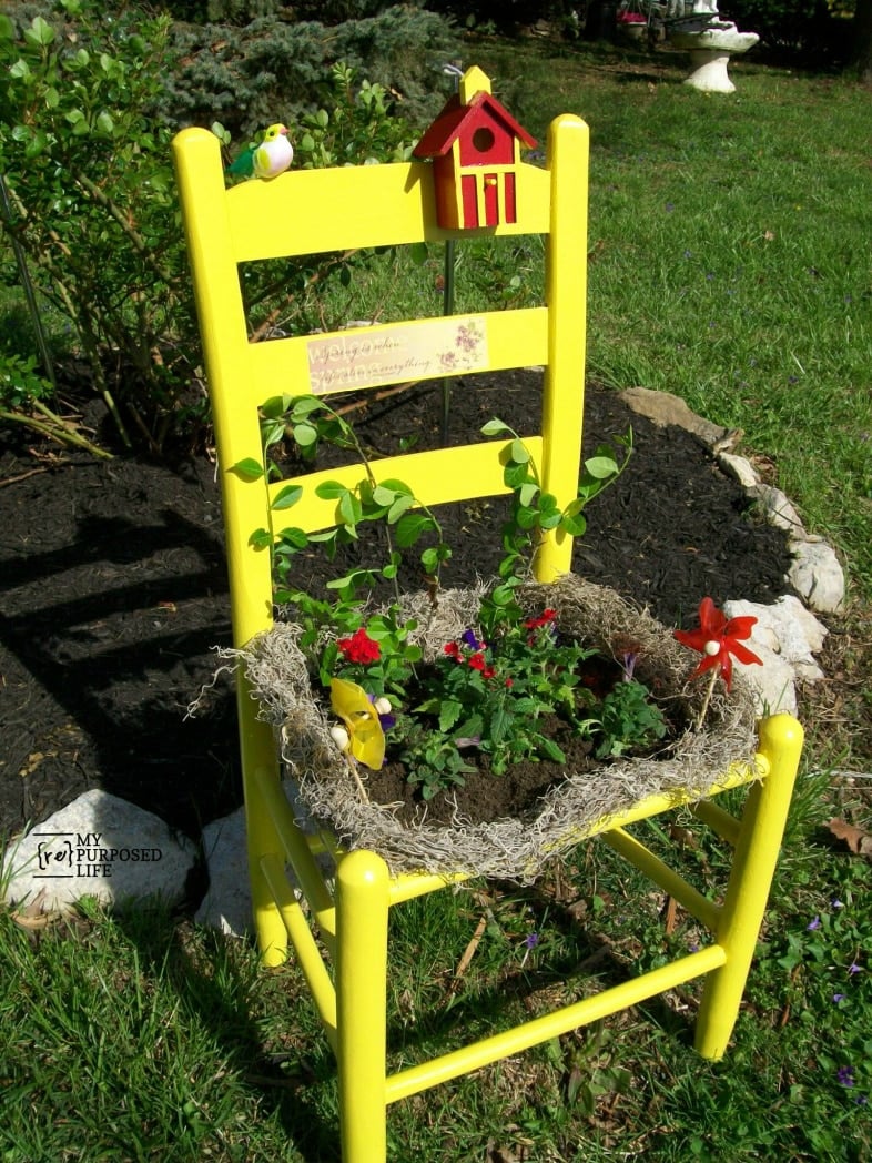 bright yellow chair in the garden holding flowers