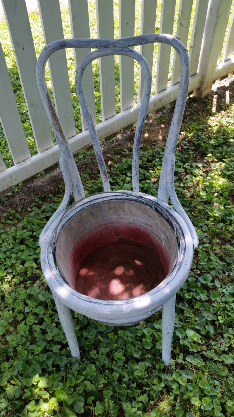 white chair with a rusty bucket in the seat