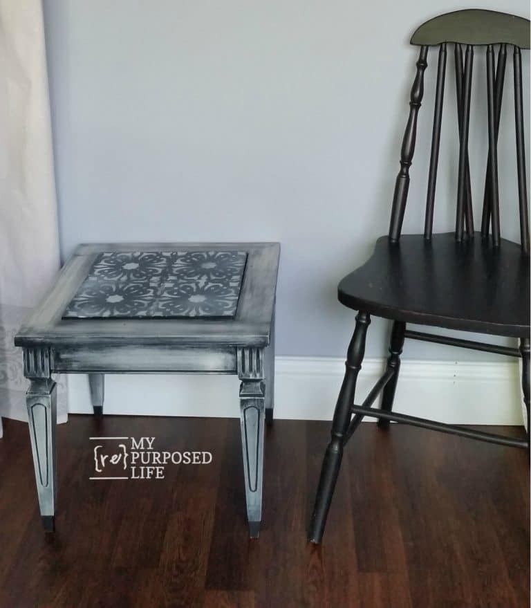 small stenciled table sitting next to a black chair