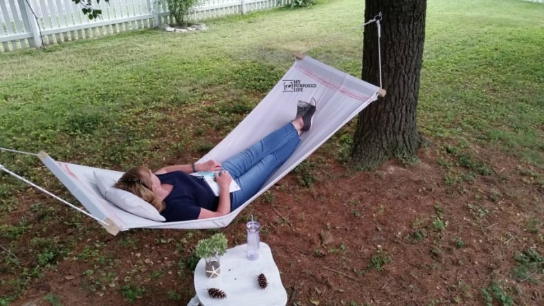 woman laying on a dropcloth hammock stretched between two trees