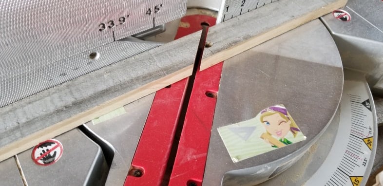cut weathered fence board on miter saw to make rustic frame