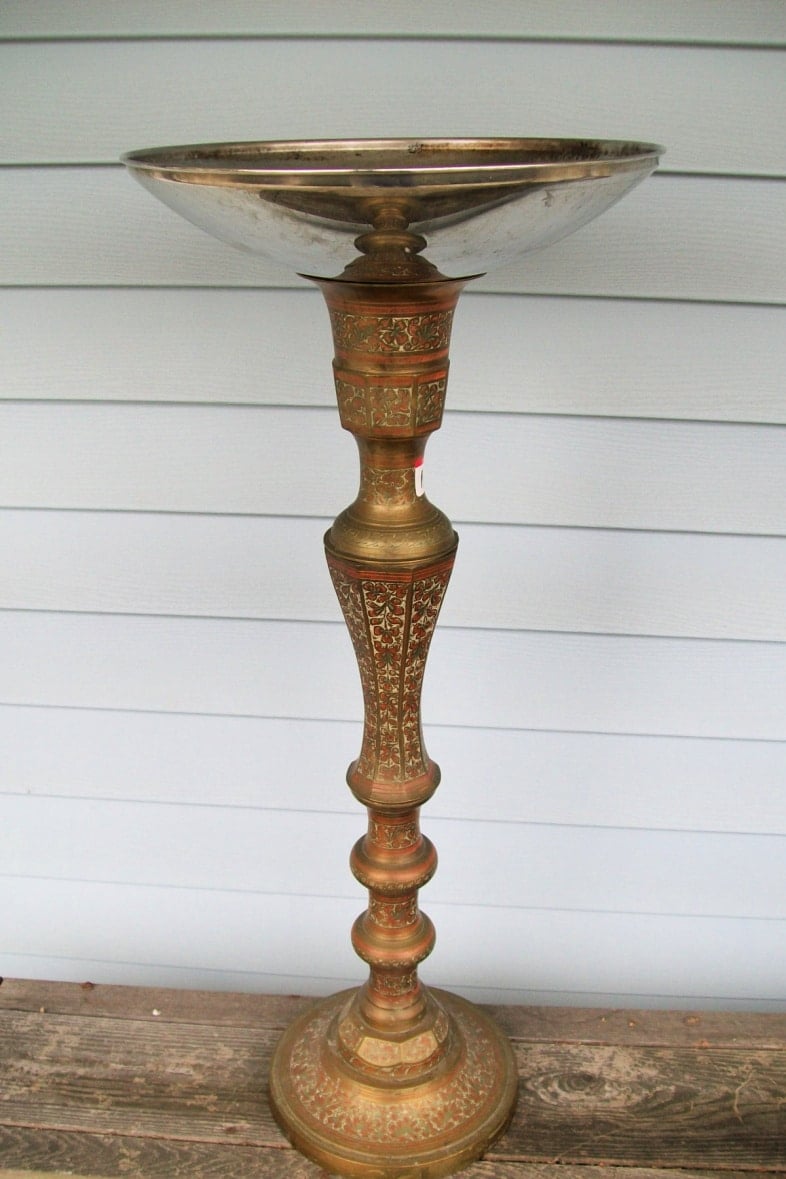 large candlestick with a large shiny pot lid on top