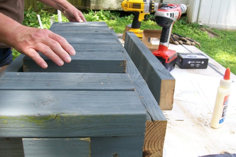 woman placing small 2x4s onto bench frame