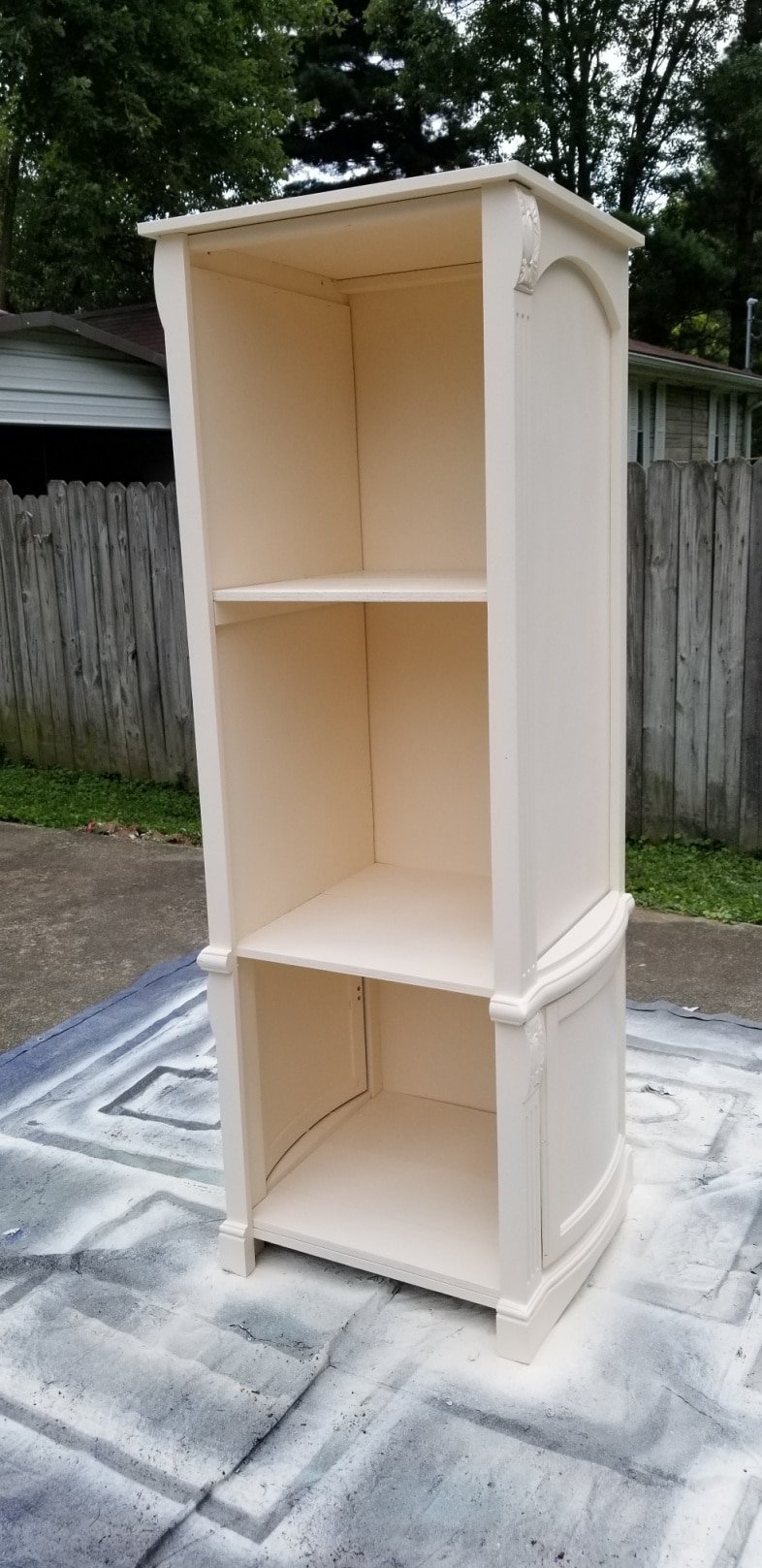 front view of white book shelf resting on a drop cloth
