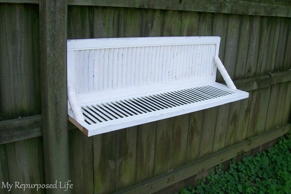 white chippy shutter shelf made with bi-fold doors hanging on fence
