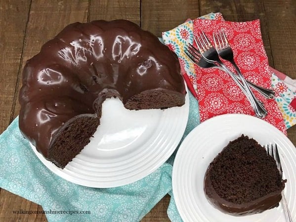 Chocolate-Brownie-Cake-on-white-serving-plate-with-a-piece-sliced
