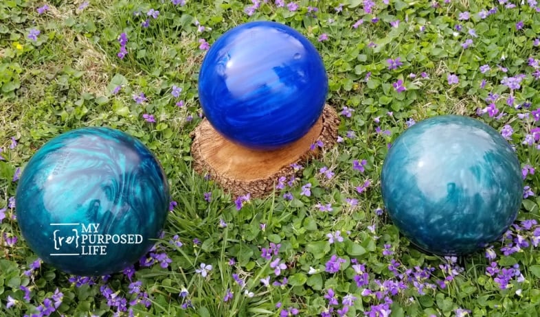 three shiny diy gazing balls made from bowling balls in the grass