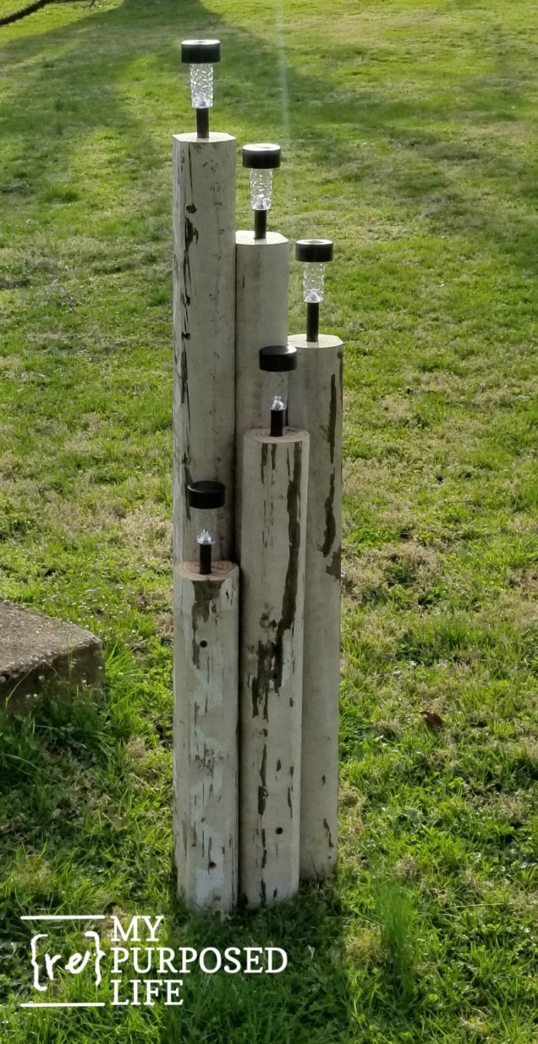 dollar store solar lights on landscape timbers standing in the yard