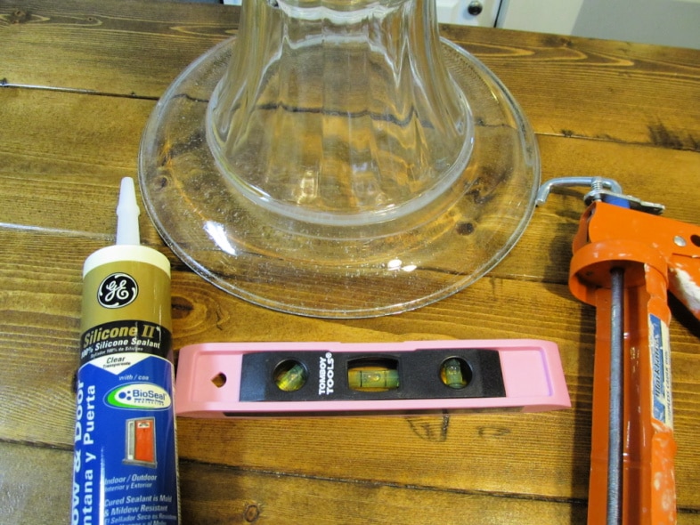 platter, vase, adhesive, level and caulk gun to make glass totems