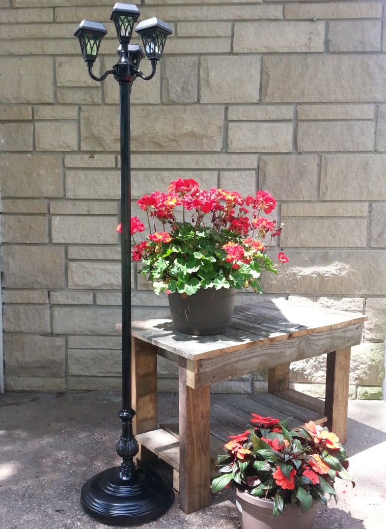 repurposed floor lamp into a solar light sitting on a porch with flowers