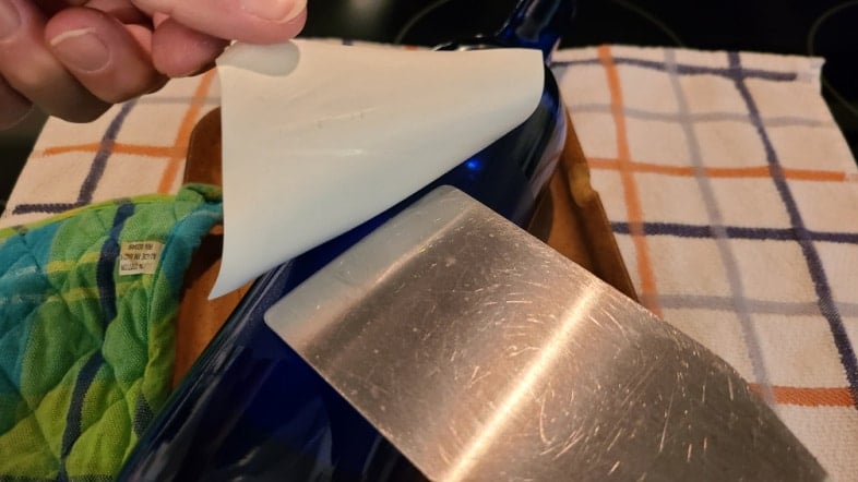 pry wine bottle label off with flat spatula