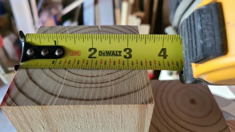 tape measure showing a 4x4 post is three and one half inches