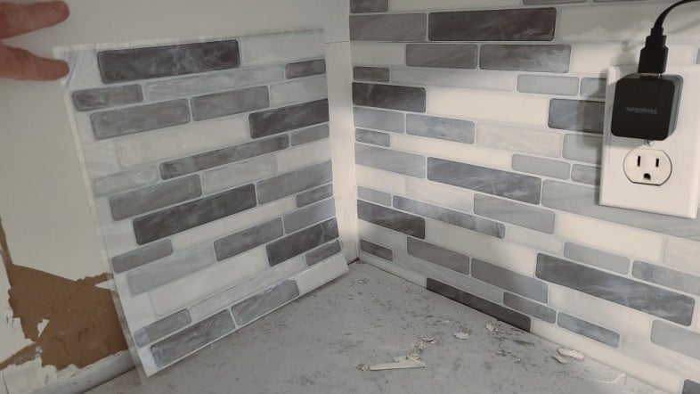 woman placing peel and stick tiles in corner