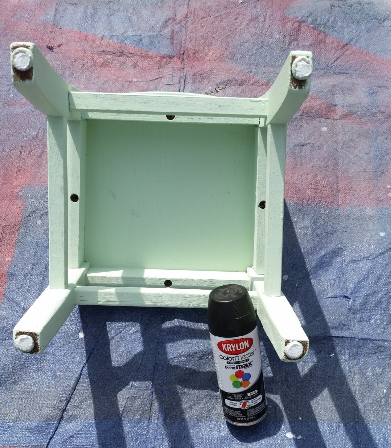 upside down green chair with a can of black spray paint