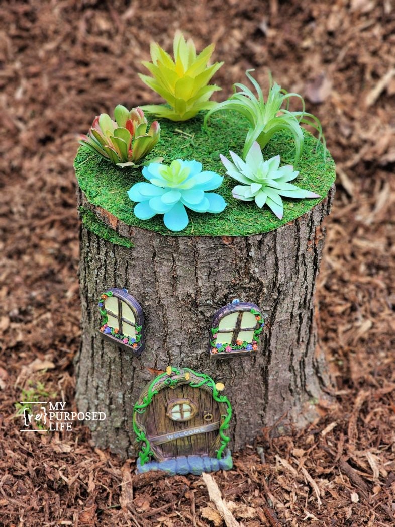 a tree stump with faux succulents 