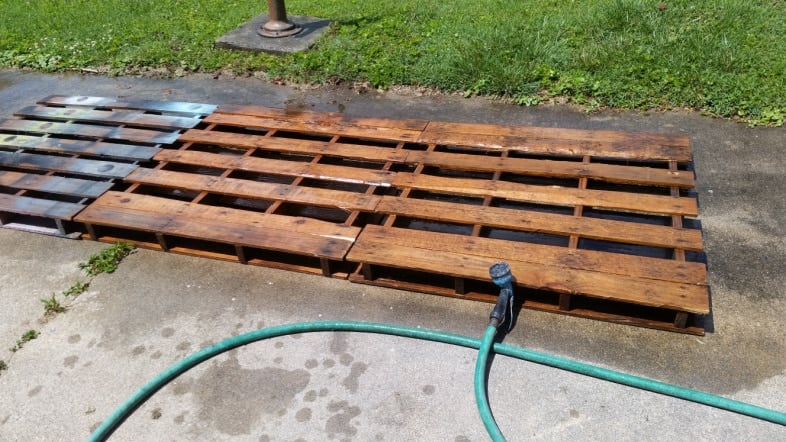 three dirty pallets and a garden hose
