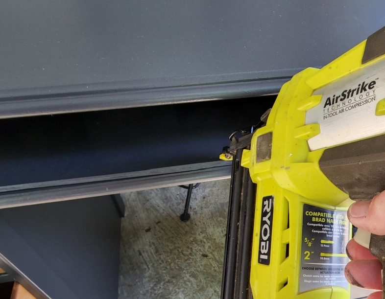 nail gun securing new shelf in old desk