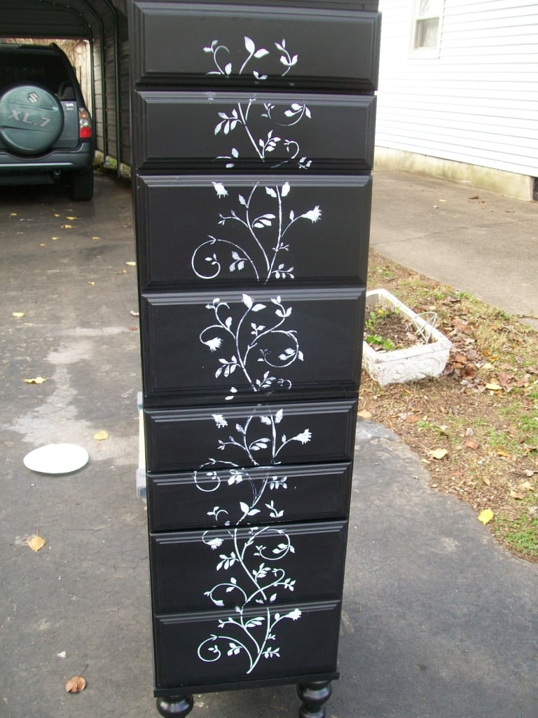 a black lingerie chest standing upright with the light gray floral stencil design on all drawers
