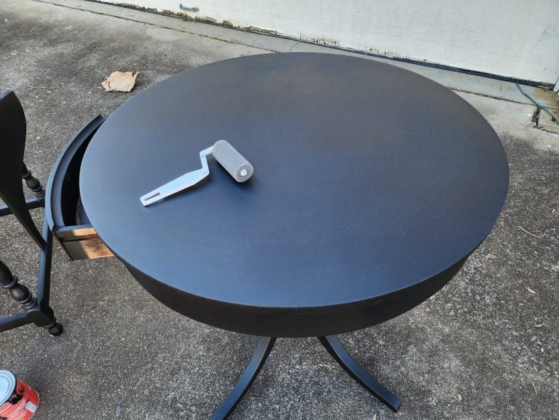black drum table with a small paint roller on it
