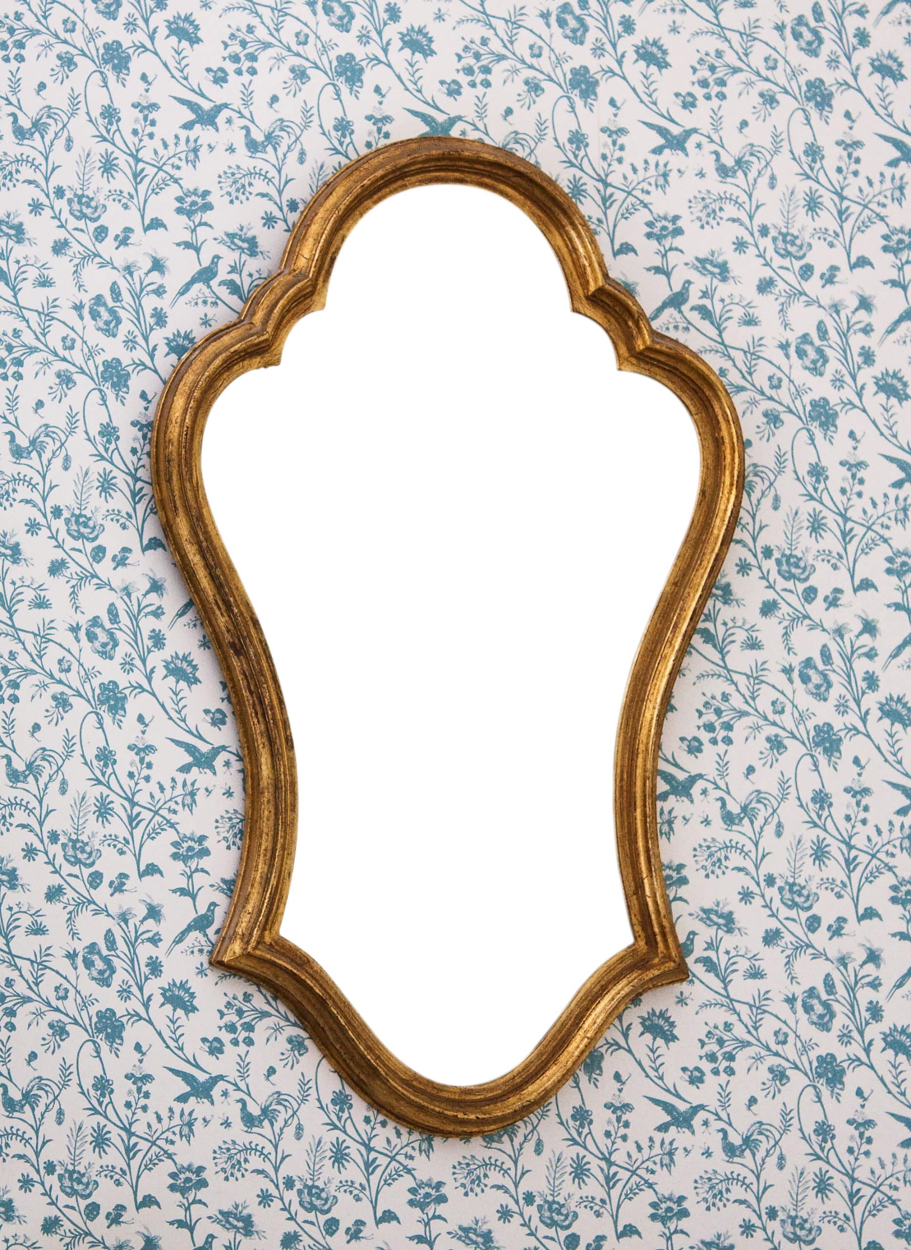 mirror hanging on floral wallpaper