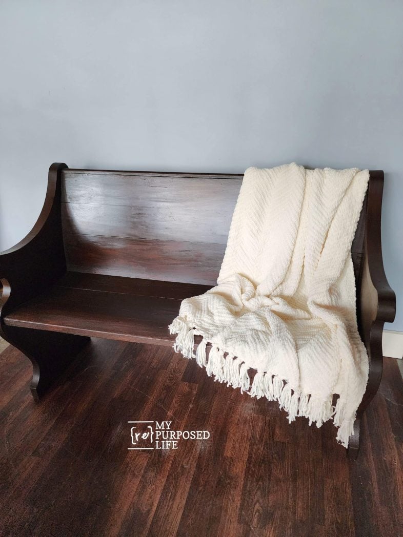 pretty stained pew with a throw over the back