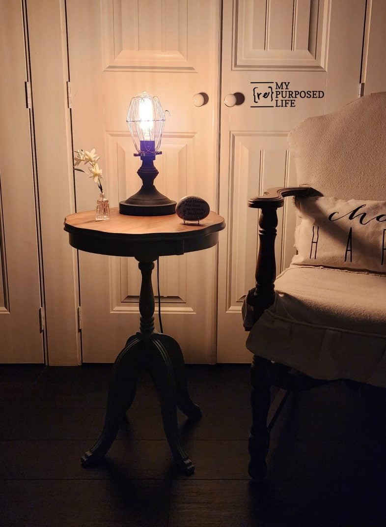 a glowing lamp lit on an antique parlor side table