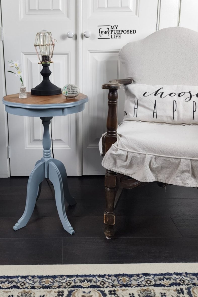 blue antique parlor side table with a lamp sitting next to a parlor chair