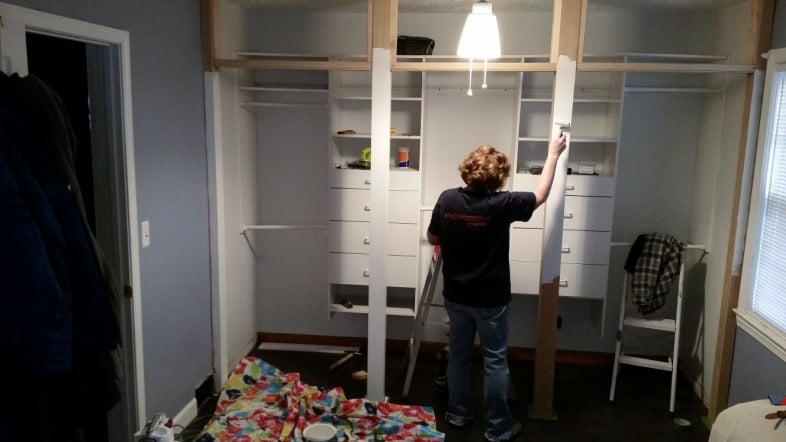 woman painting front facing of new closet framing with a small roller