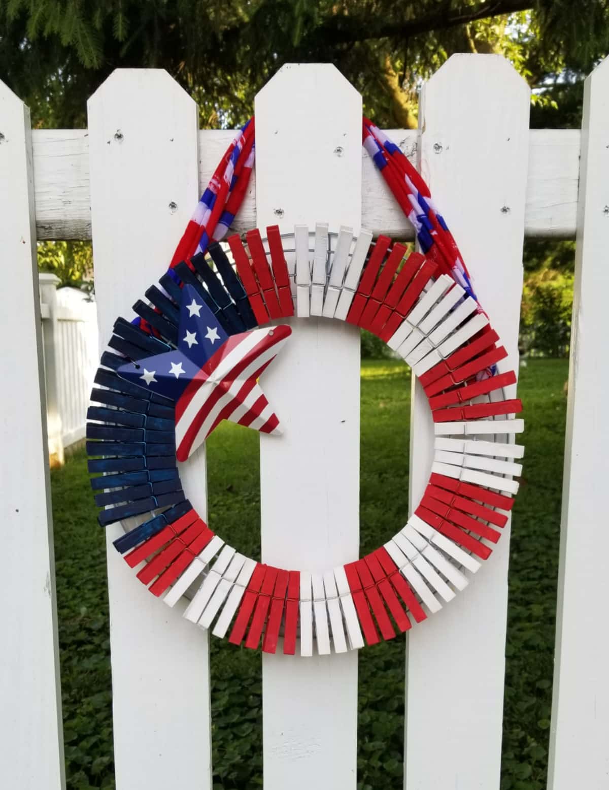 red white and blue clothespin wreath on white fence