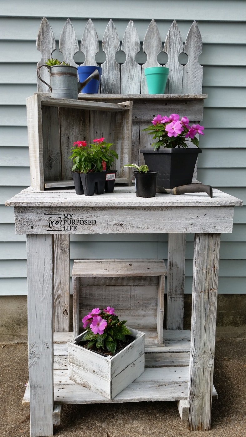 whitewashed potting bench with flower pots and tools