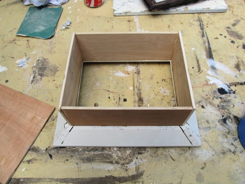 four pieces of plywood resting in shadow box frame to test fit