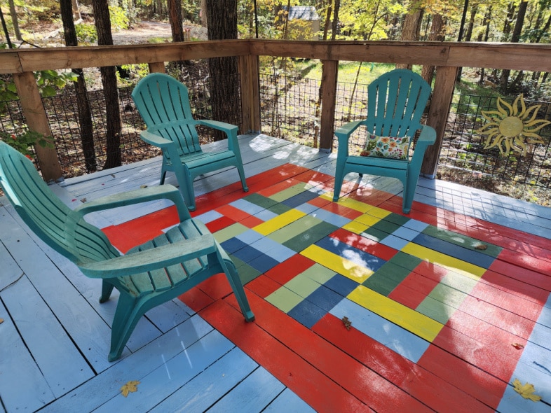 chairs on a deck with a bright painted porch rug in primary colors