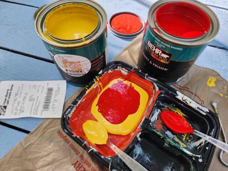 mixing yellow and red paint in plastic container