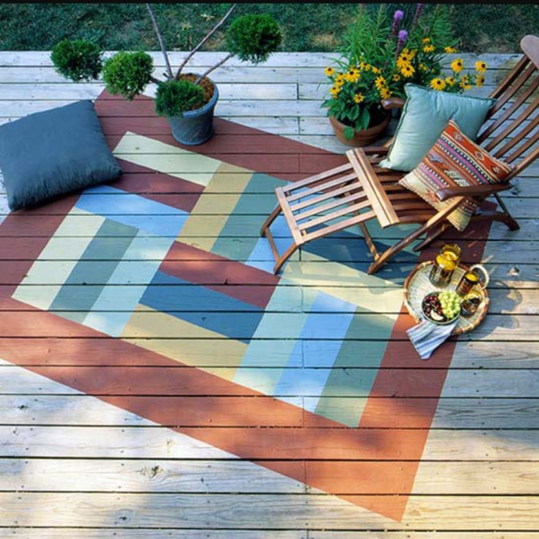 colorful deck rugh with pillows, chaise lounge and flowers
