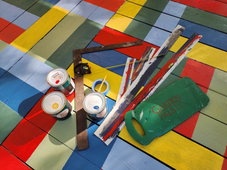 paint and supplies laying on painted porch rug