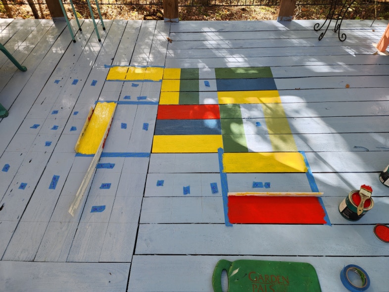 partial painted porch rug with blue pieces of painter's tape