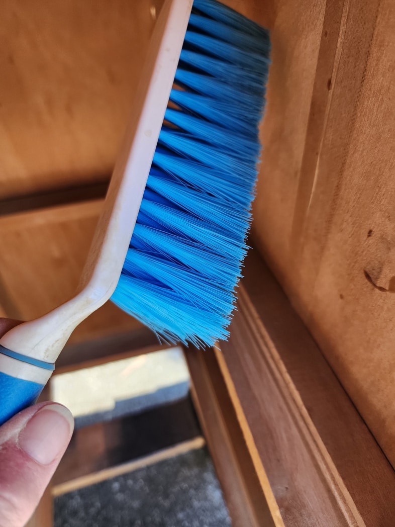 hand broom cleaning the inside of the desk