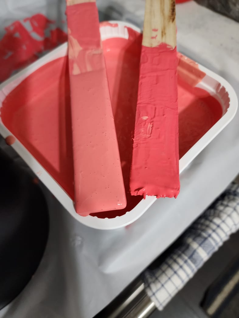 a container with two different color pink paint sticks