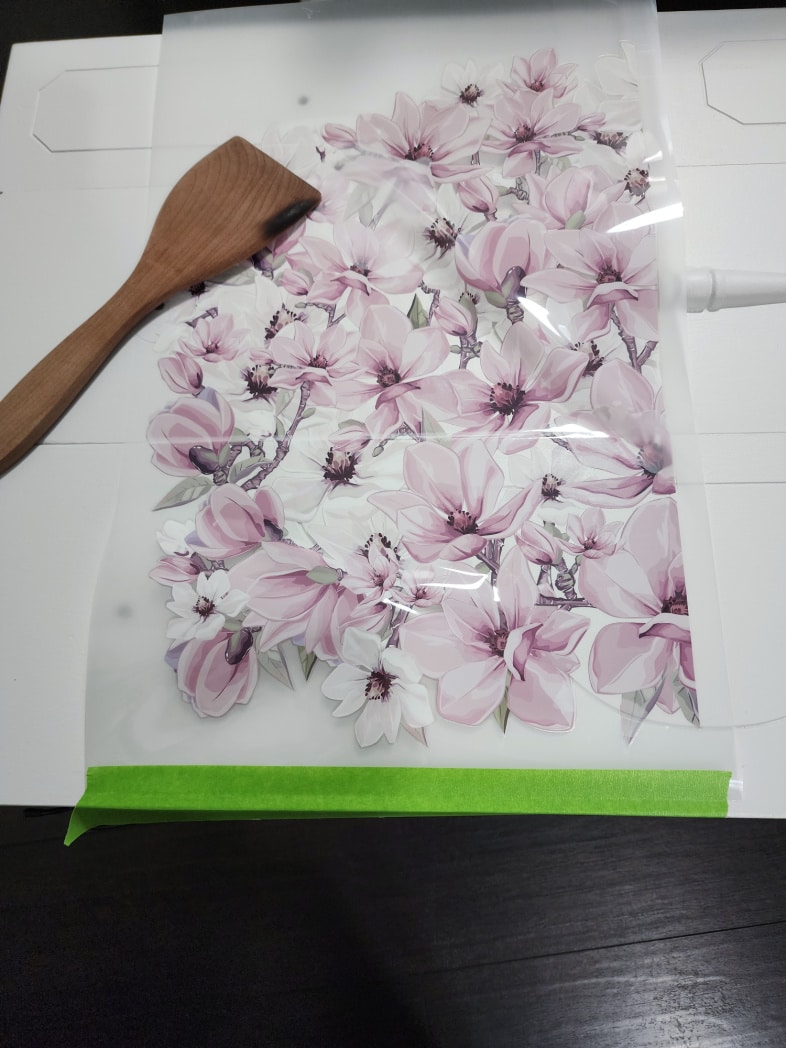 green painter's tape holding flower furniture transfer on drawers-a wooden spatula