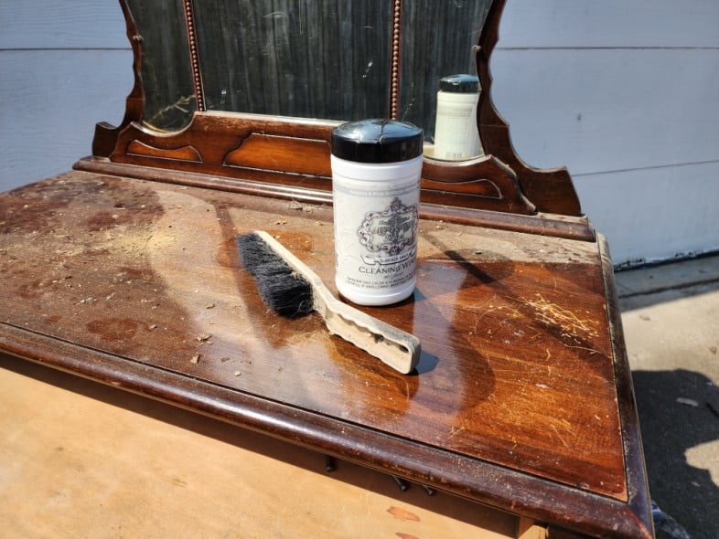 top of antique dresser with a dust brush and surface preps wipe container
