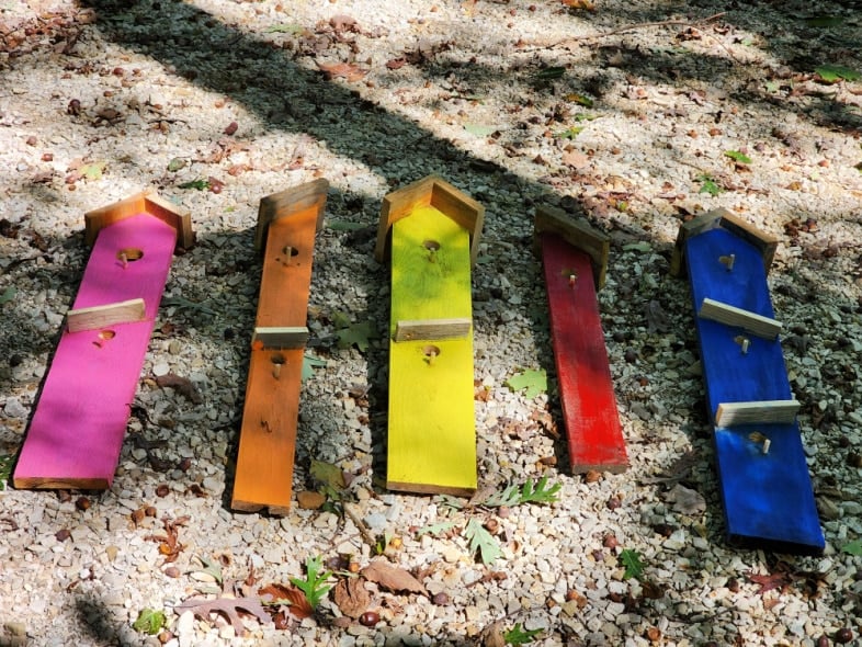 colorful diy faux birdhouse boards laid out on the gravel driveway