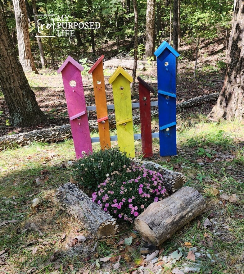 colorful faux birdhouse decor in the flower garden